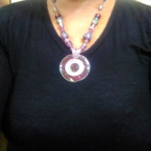 Woman necklace with purple medallion.